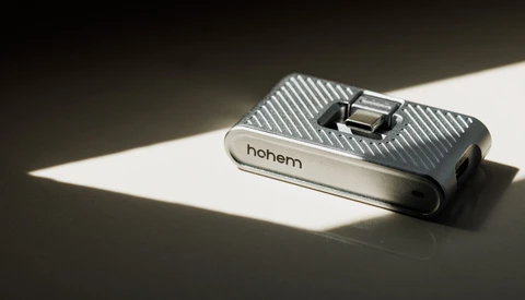 Hohem smartphone gimbal stabilizer on white surface with dramatic diagonal sunlight creating sharp shadow contrast.