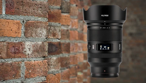 Viltrox AF 35mm f/2.8 lens with lens hood attached, displayed against a brick wall background.