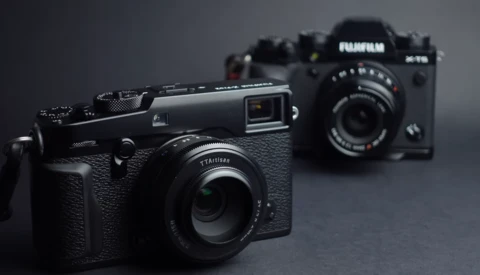 Three rangefinder-style digital cameras arranged on a gray surface with selective focus on the foreground model.