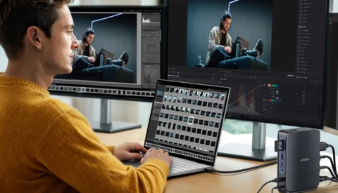 Video editor working at dual monitors with control panel and editing software open.