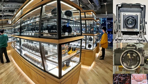 Illuminated display cases in a camera equipment showroom with vintage and modern cameras on shelves.