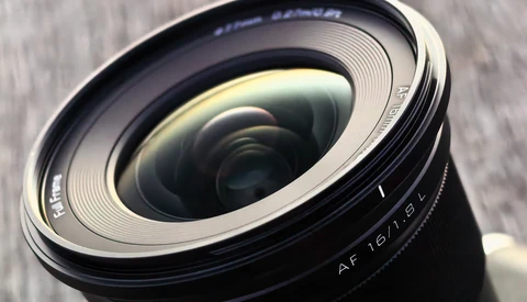 Close-up of a wide-angle lens showing the front element and autofocus markings with textured surface details.