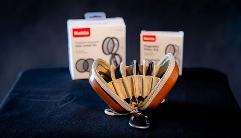 Makeup brush set with wooden handles displayed in an orange leather case alongside product packaging.