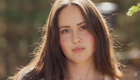 Portrait of a young woman with long dark hair in golden hour sunlight.