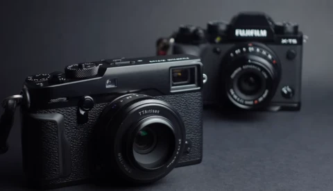 Three rangefinder cameras arranged on a gray surface with selective focus on the nearest black camera.