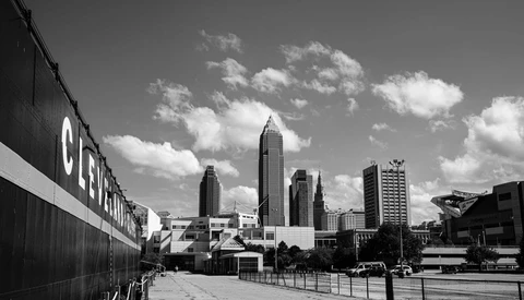 Black and white cityscape featuring tall art deco skyscrapers under dramatic clouds.
