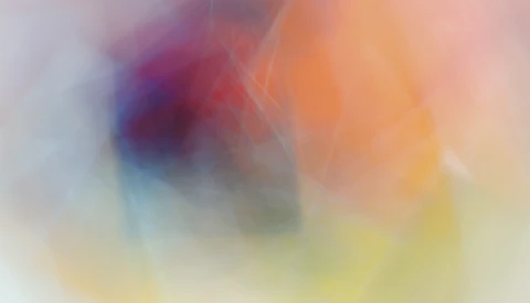 Abstract gradient background with blurred color transitions from blue and purple to orange, yellow, and cream tones.