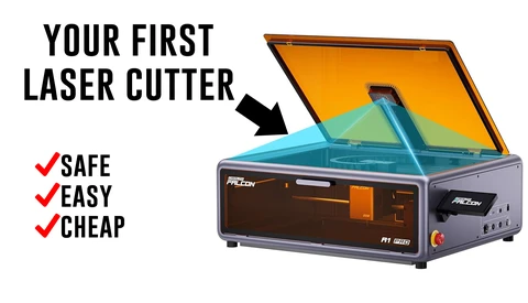 Illustration of a compact desktop laser cutter with an open orange lid and blue interior chamber.
