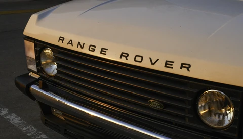 Classic Range Rover front end with cream-colored hood and black grille in daylight.