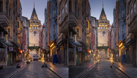 Galata Tower illuminated at dusk in Istanbul, framed by historic buildings along a narrow cobblestone street.