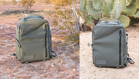 Two olive-green travel backpacks displayed side-by-side on desert ground with cacti and rocks in background.