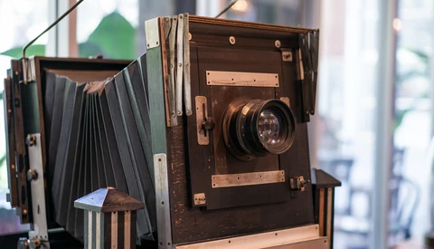 Vintage large-format view camera with bellows and lens, displayed in natural window light.