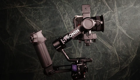DJI Ronin gimbal with mounted smartphone stabilizer on textured dark background.
