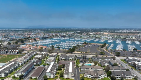 Aerial view of a coastal residential community with a large marina filled with white boats.