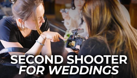 Female videographer operating a mirrorless camera while another woman looks on during a production setup.