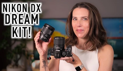 Woman holding a Nikon DX camera body and lens against a colorful blurred background.