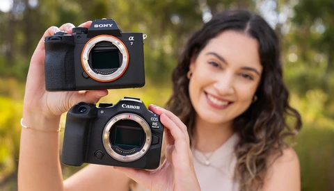 Woman holding a Sony α and Canon EOS R5 camera body side by side outdoors.
