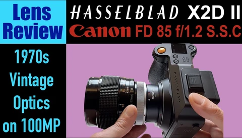 Hasselblad X2D II camera with Canon FD 85mm f/1.2 S.S.C lens mounted, held in hands against pink background.