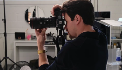 Cameraman operating cinema camera on tripod in studio setting