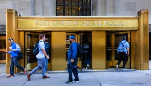 People in blue shirts entering a gold-framed entrance to Two North Riverside Plaza