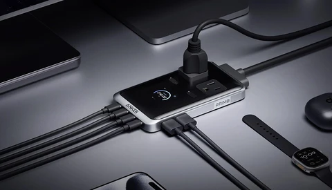Smartphone with USB charging hub connected to multiple cables on minimalist desktop