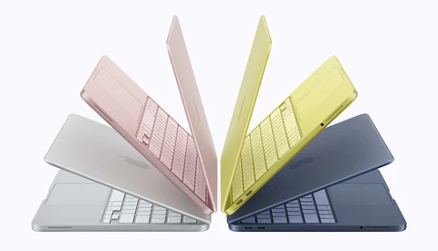 Illustration of five laptop computers arranged in a fan pattern, displaying various pastel colors including pink, white, yellow, and dark blue.