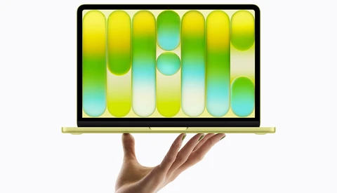 Laptop displaying a vibrant wallpaper with gradient-filled pill shapes in yellow, green, cyan, and white tones.