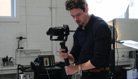 Videographer operating a motorized gimbal stabilizer in a bright studio space