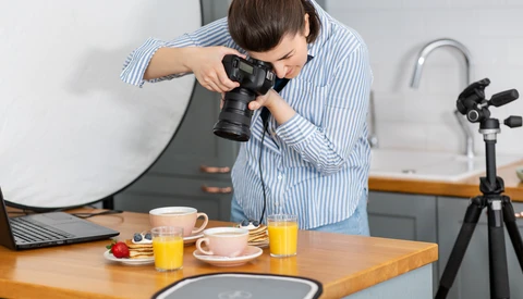 Photographer shooting a styled food setup with a mirrorless camera on a tripod in a bright kitchen.