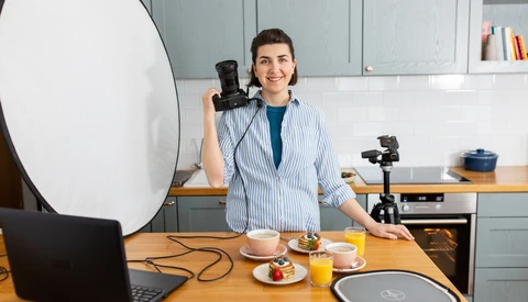 Content creator in a kitchen studio with professional lighting setup and camera equipment.