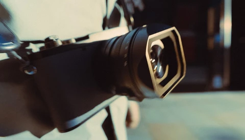 Close-up of a camera lens with a gold square filter holder mounted on the front.