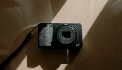 Ricoh GR compact digital camera viewed from above with natural window light casting shadows.