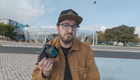 Photographer holding a thermal imaging camera while posing outdoors in urban setting.
