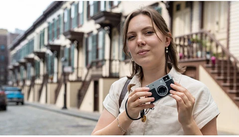 Woman holding a vintage film camera on a European street lined with classical architecture