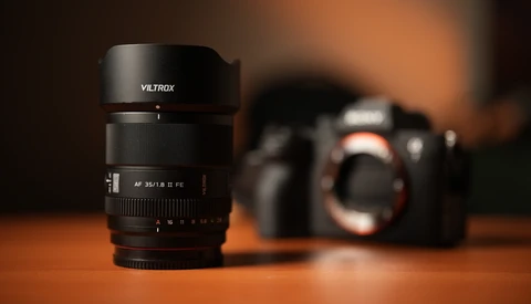 Viltrox AF 35mm f/1.8 lens in sharp focus on wooden surface with camera body blurred in background.