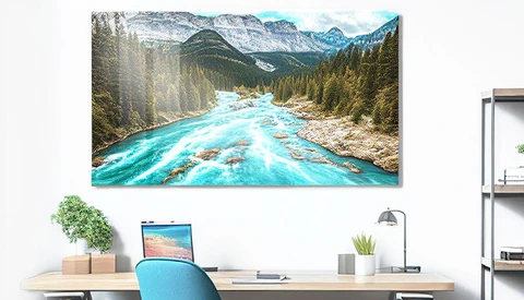 Turquoise river flowing through forested valley with snow-capped mountains in background.