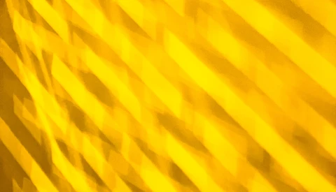 Abstract yellow diagonal lines creating a textured pattern with shadow and light variation
