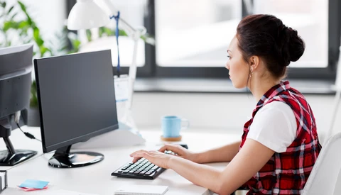 Woman at desk working on desktop computer in bright office environment