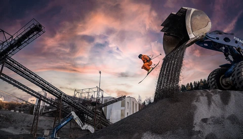 Skier launching airborne from industrial landscape at golden hour