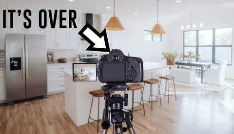 DSLR camera on tripod displaying kitchen interior on its rear screen with arrow pointing downward and 'IT'S OVER' text overlay.