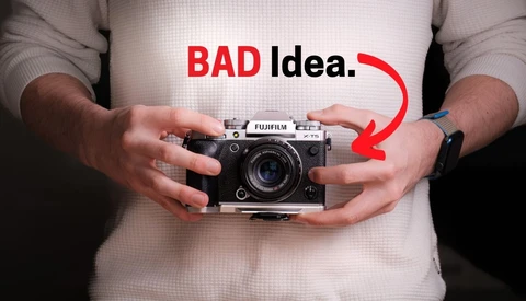 Person holding a rangefinder film camera with text overlay reading "BAD idea" and a red arrow pointing to the camera.