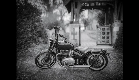 Classic motorcycle parked on a street with traditional Asian architecture in the background.
