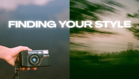Hand holding a vintage rangefinder camera against a blurred mountainous landscape background.