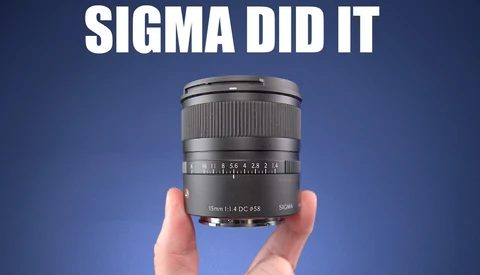 Sigma 16mm f/1.4 DC HSM lens held in hands against blue background.