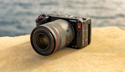 Canon EOS R5C mirrorless camera with RF lens on sandy beach with ocean in background.