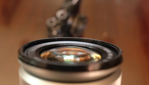 Close-up of a camera lens with shallow depth of field, showing glass elements and black barrel