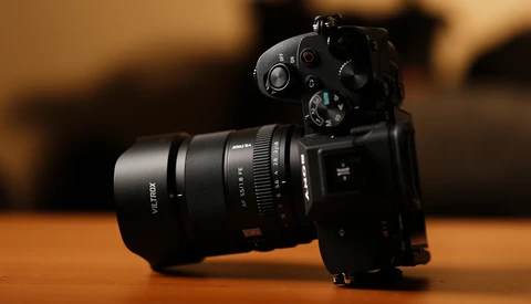 Black mirrorless camera with attached telephoto lens on wooden surface