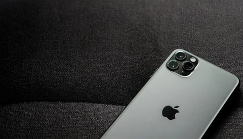 Silver iPhone 11 Pro with quad camera system on dark textile surface