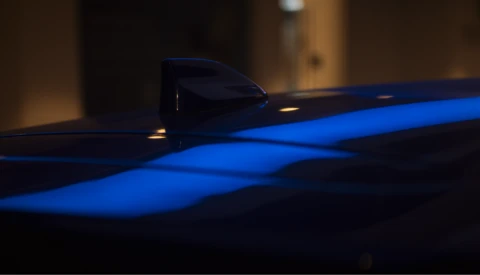 Blue neon light tube creating geometric patterns against dark background with shallow depth of field