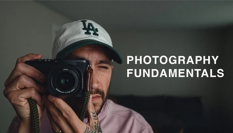 Photographer holding a Leica rangefinder camera, wearing LA Dodgers cap